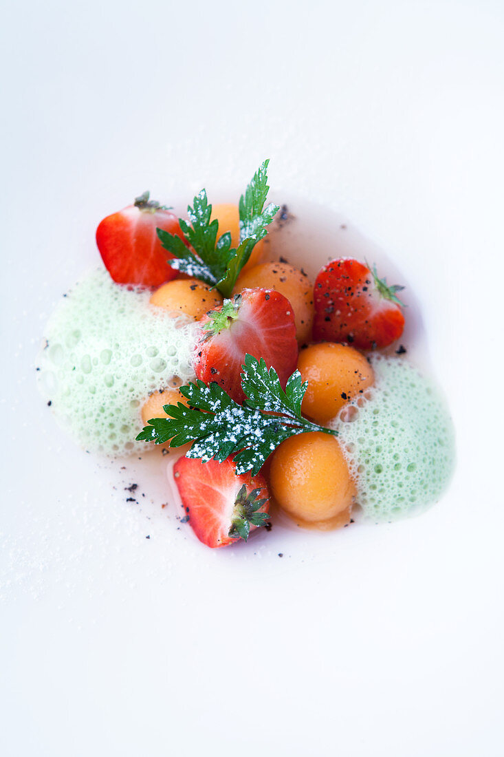 Melon balls and strawberries in a port wine broth with parsley foam
