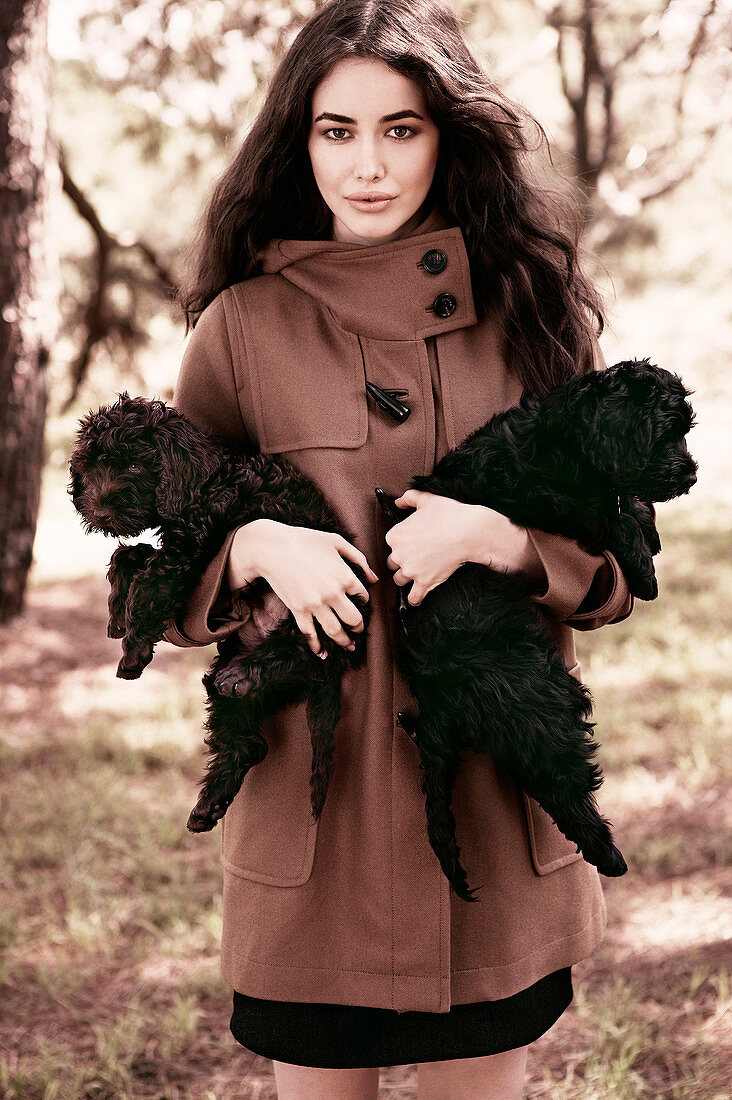 A dark-haired woman wearing a brown coat with two dogs