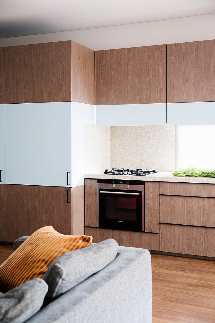 Einbauküche mit mit holzfarbenen und weißen Fronten in offenem Wohnraum