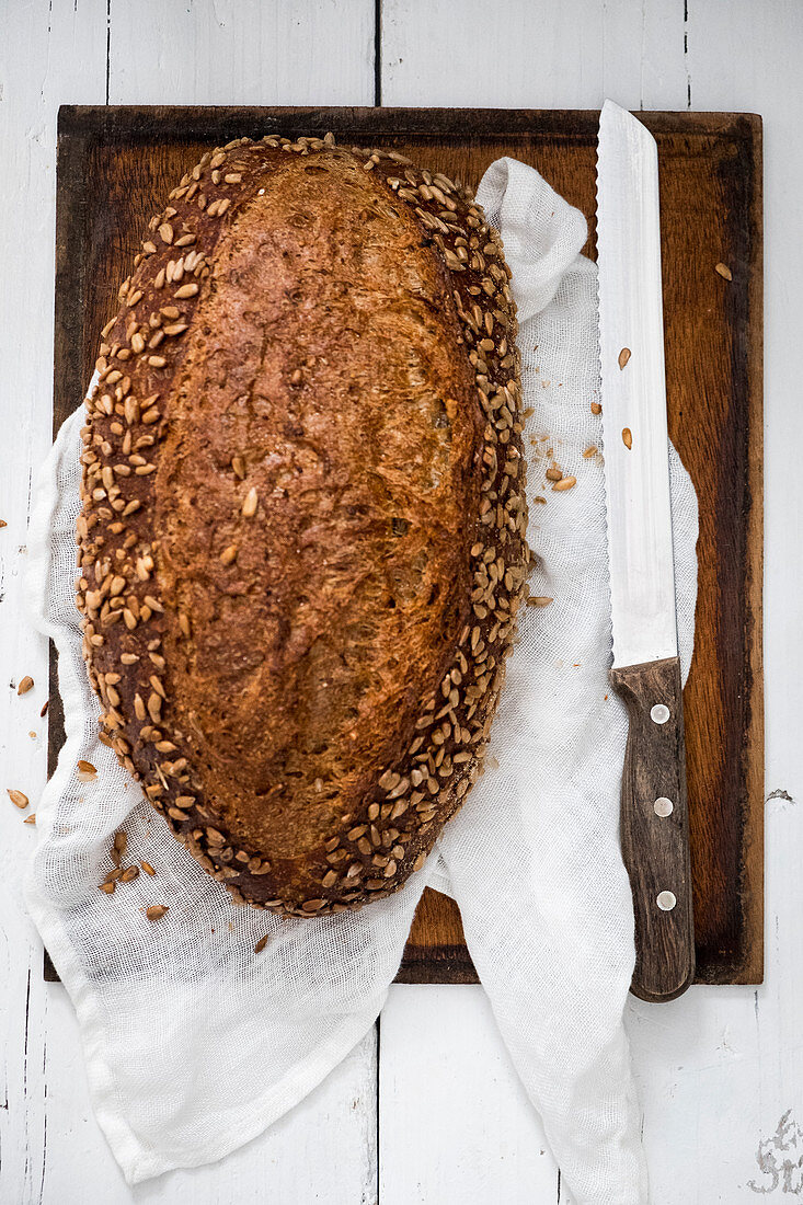 Körnerbrot auf Holzschneidebrett mit Brotmesser