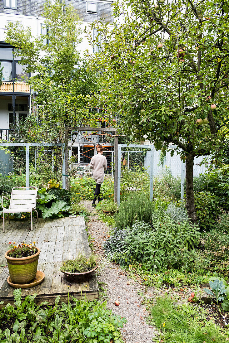 Woman walking through cottage garden with weathered terrace