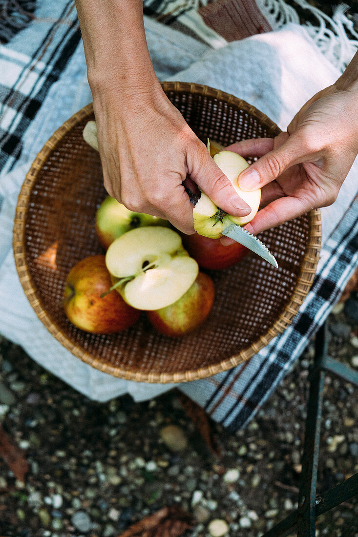 Hände schälen Äpfel über einem Korb