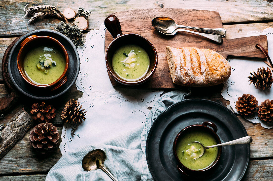 Zucchini soup in 3 bowls on a wooden table with autumn decorations from the wood