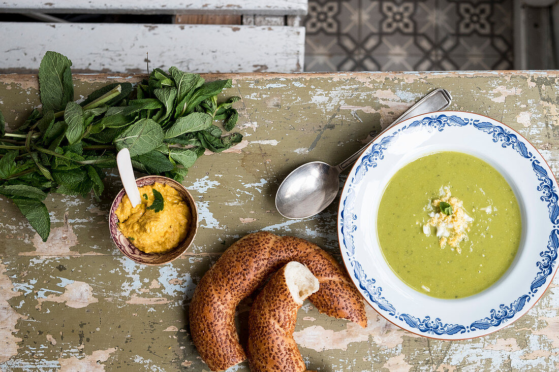 Peas soup on a table with fresh bread and hummus from above