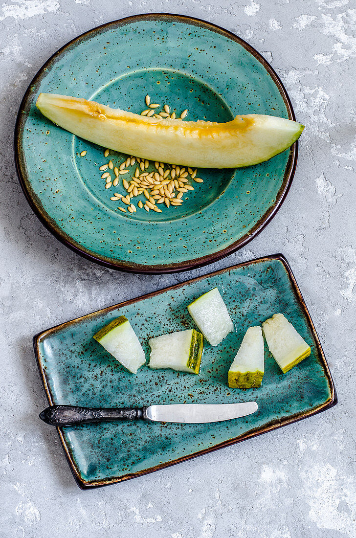 Aufgeschnittene Futuro-Melone mit Kernen auf türkisen Tellern