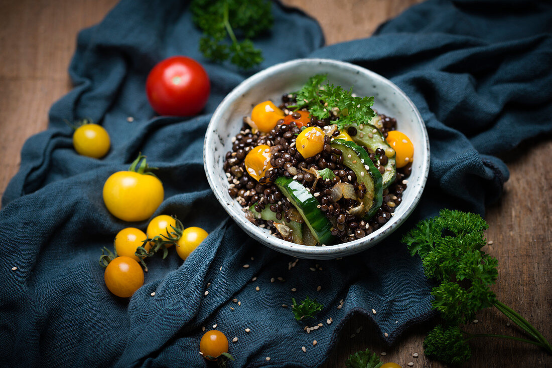 Veganer warmer Linsensalat mit Gurken, Tomaten, Zwiebeln und Sesam
