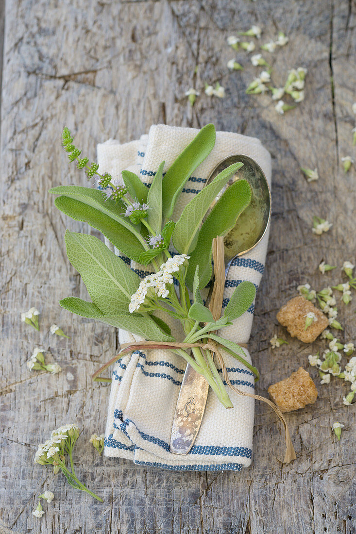 A cloth napkin with herbs and a silver spoon