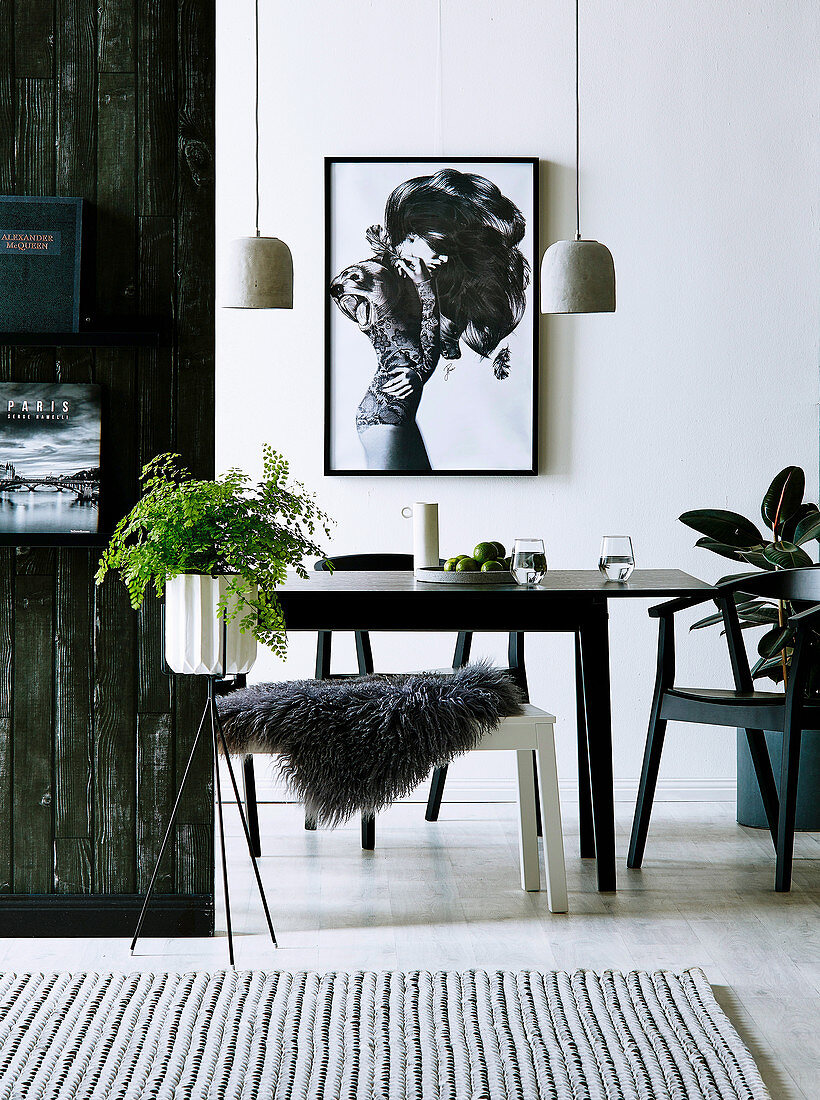 Pendant light over dining table and bench with fur blanket, houseplant in the foreground