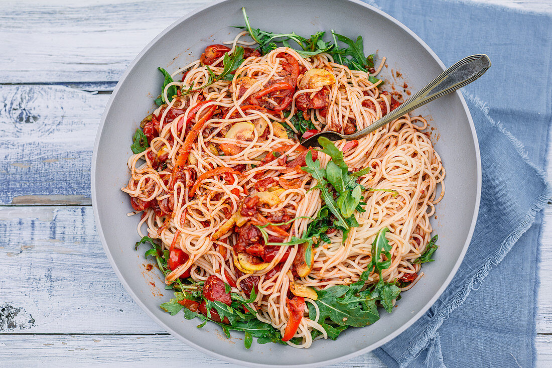 Spaghetti with rocket, peppers, tomatoes and zucchini