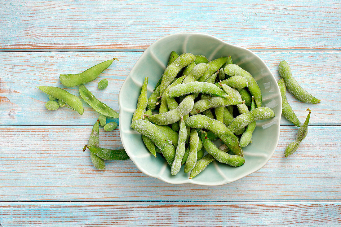 Frozen edamame in a bowl on a wooden background (top view)