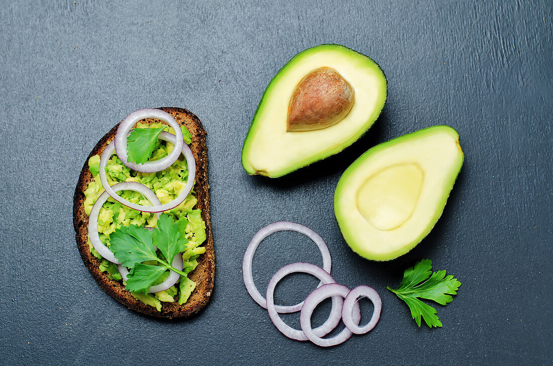 Rye breakfast sandwich with smashed avocado, red onion and parsley