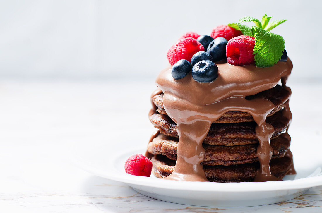 Schokoladenpancakes mit Blaubeeren, Himbeeren und Schokoladensauce