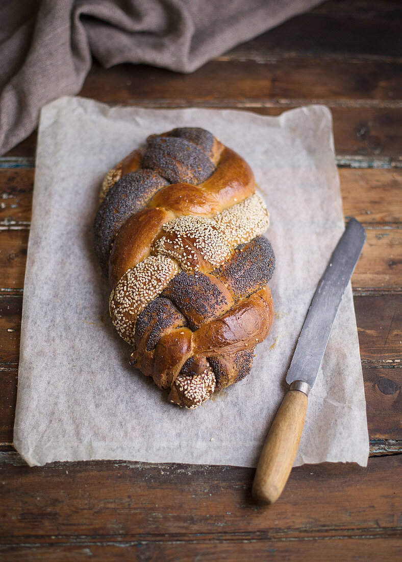 Braided bread with poppy seeds and sesame seeds on baking paper