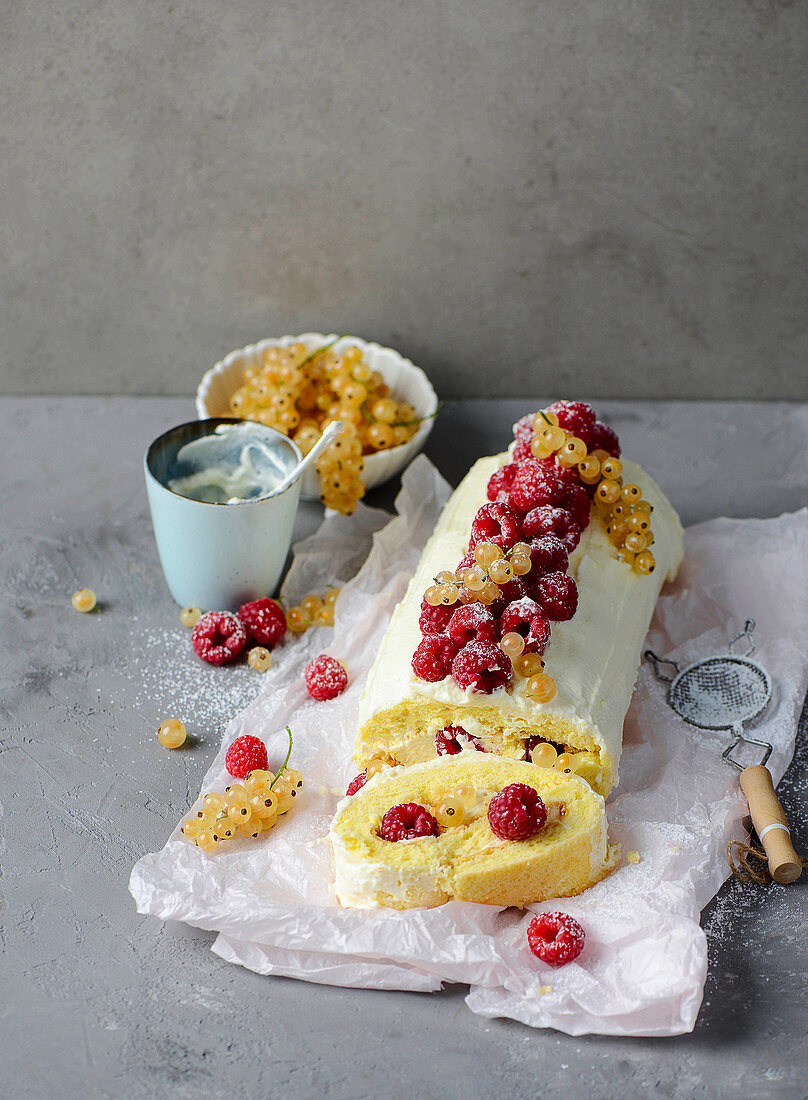 A sponge roll with raspberries and white currants