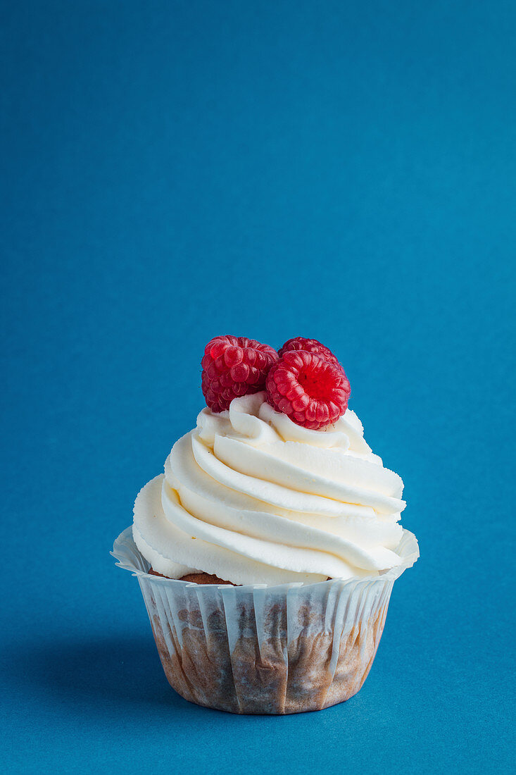 Vanilla cupcake with whipped cream and raspberries