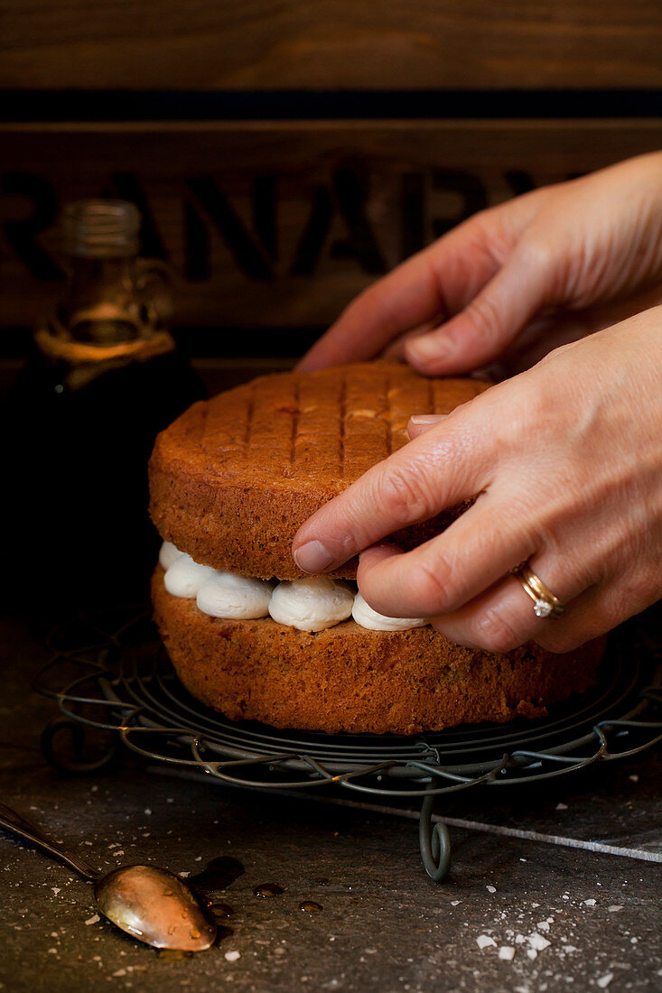A woman assembling an apple and cinnamon cake with salted maple syrup butter cream