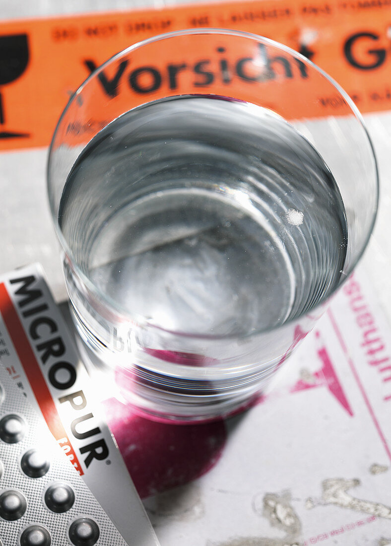 Ein Glas Wasser daneben Tabletten zur Wasserreinigung und Wasseraufbereitung