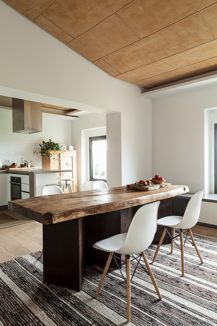 Rustic wooden table and classic chairs in open-plan interior