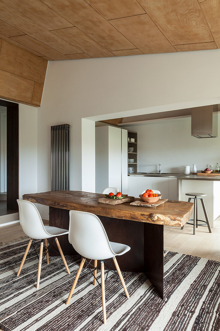 Rustic wooden table and classic chairs in front of open-plan kitchen