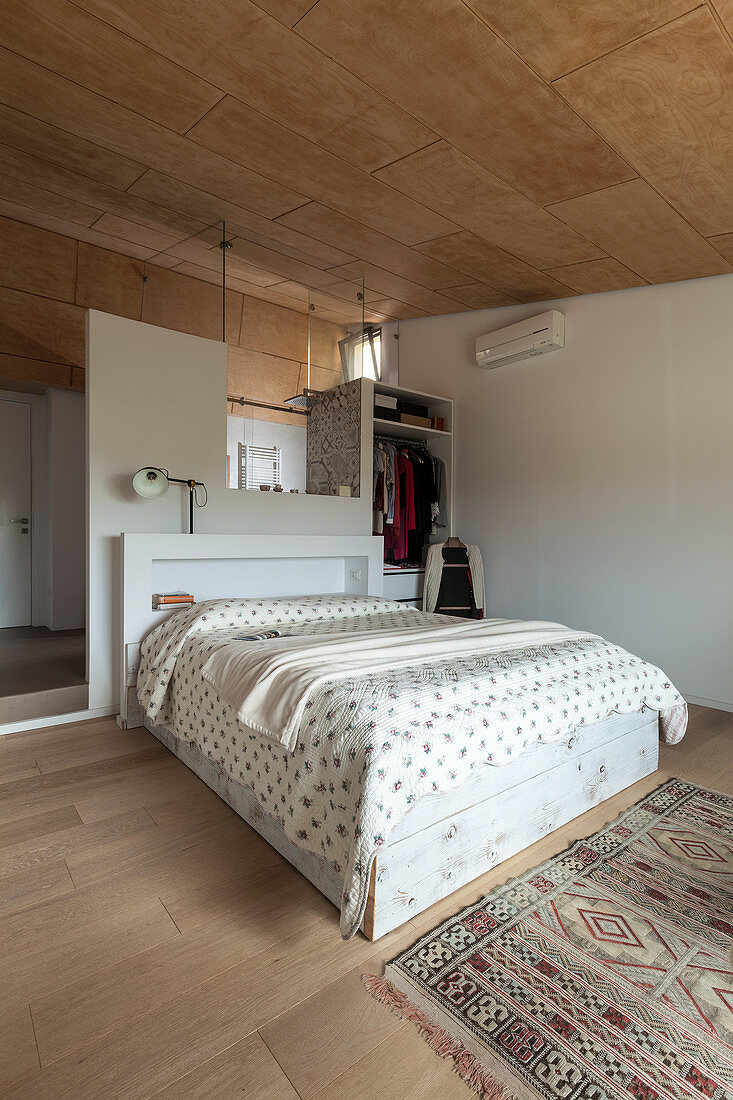 Doppelbett an Raumteiler und Kleiderschrank im Schlafzimmer