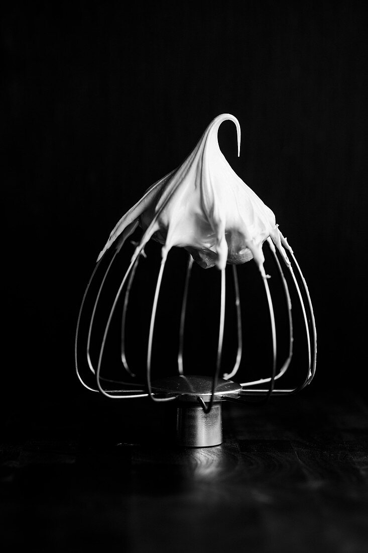 Meringue on a whisk on a black surface