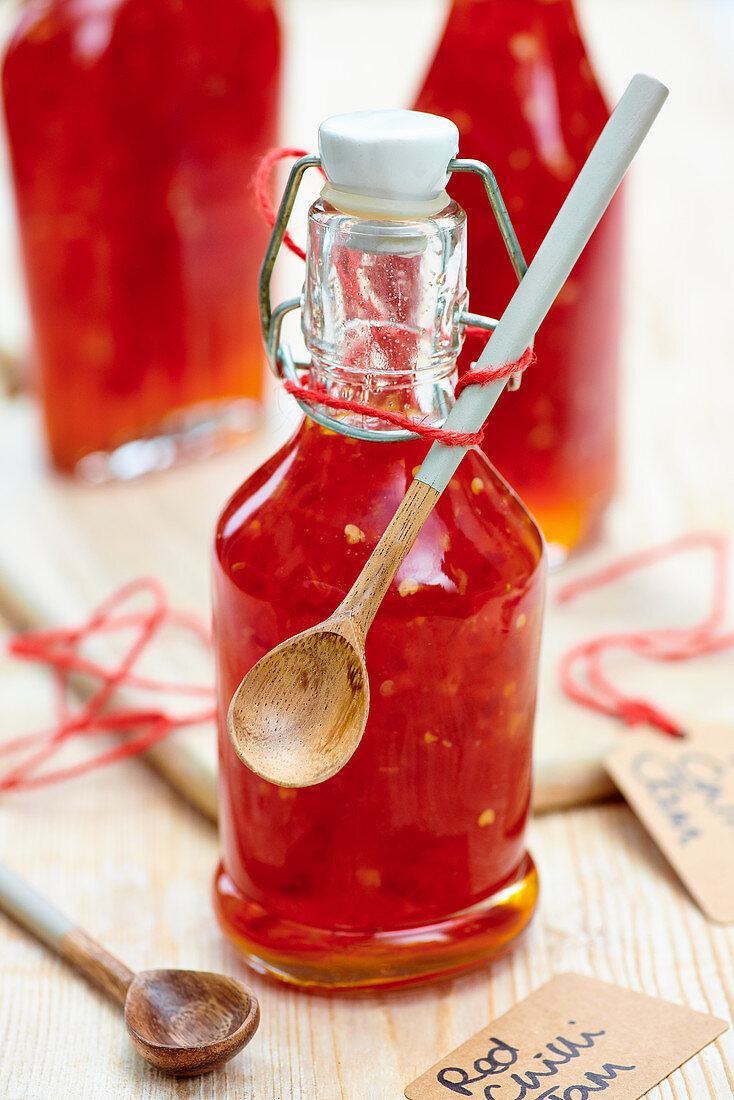 Rote Chilimarmelade in Bügelflasche mit Holzlöffel zum Verschenken
