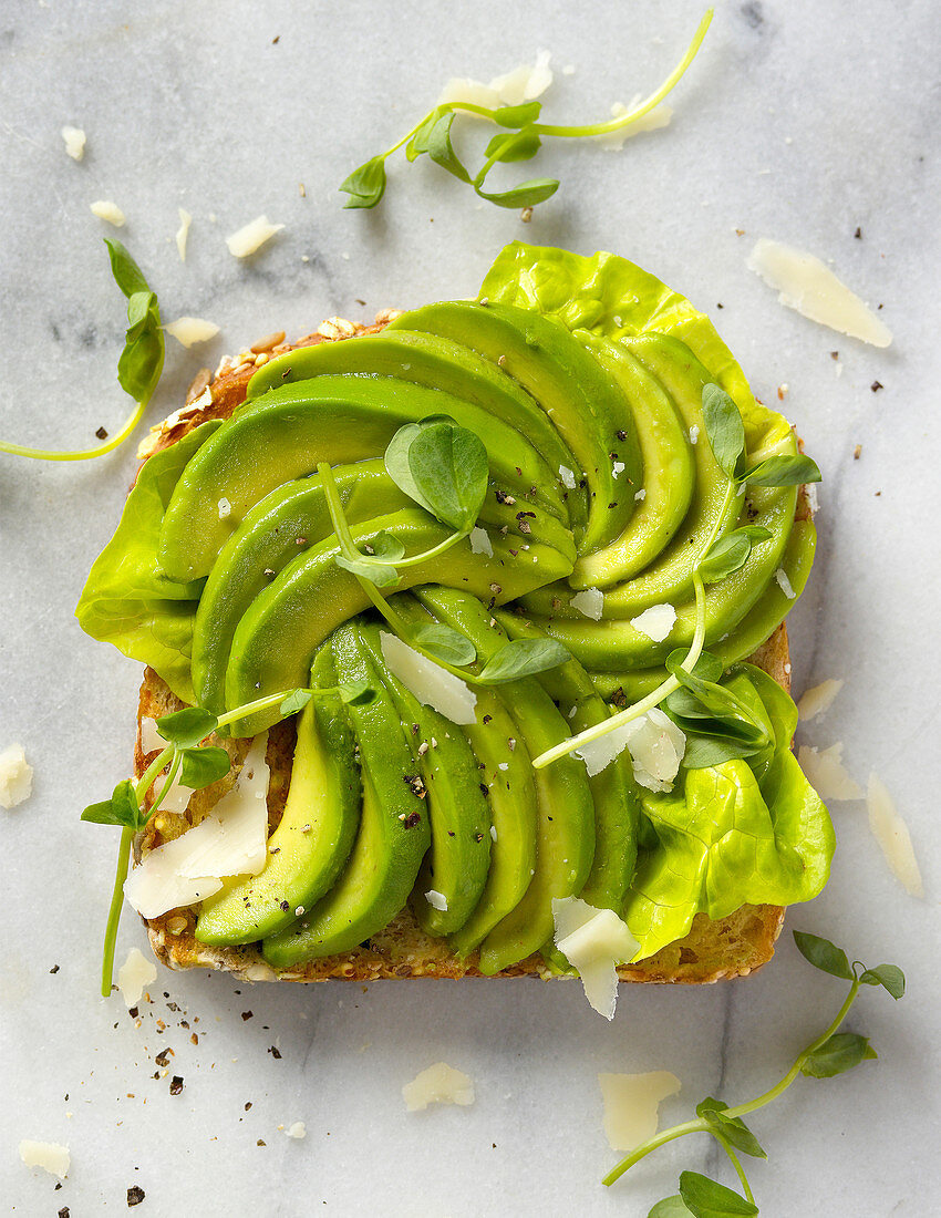 Eine Toastscheibe belegt mit Avocadospalten (Aufsicht)