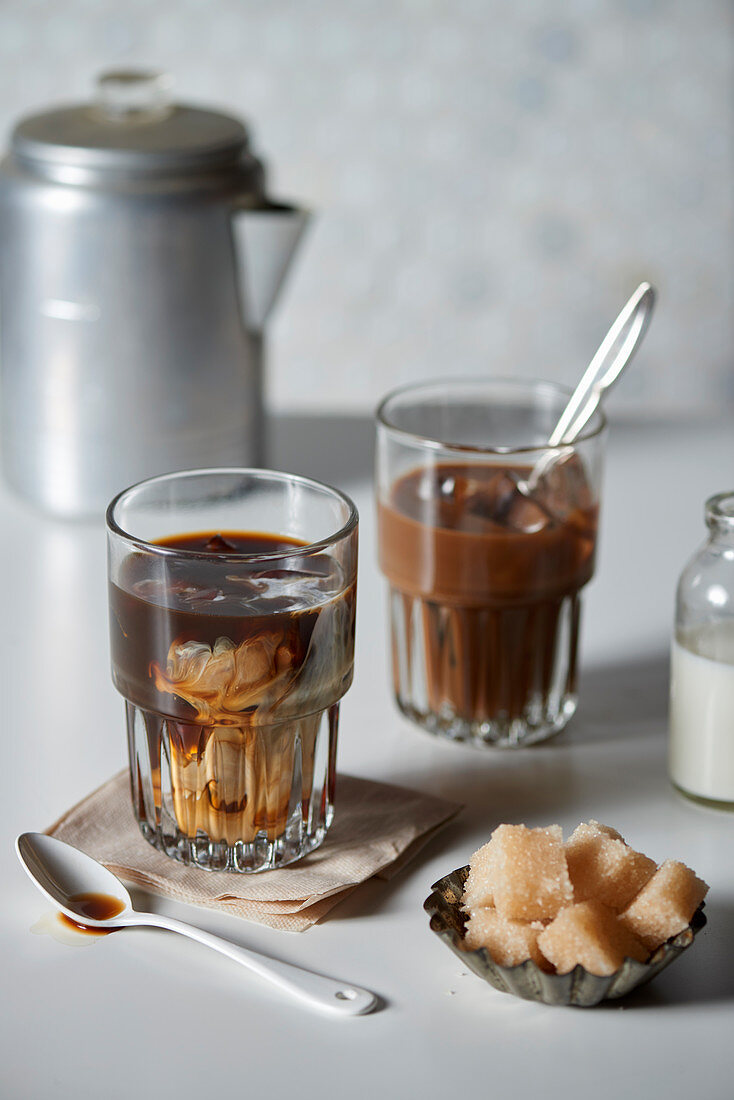 Iced coffee in a glass with cream and brown sugar cubes