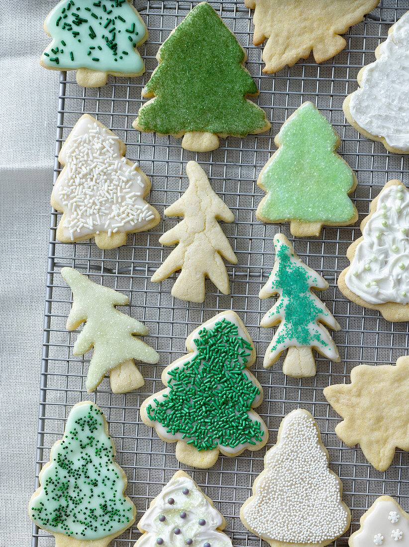 Christmas tree cookies with various decorations on a cooling rack