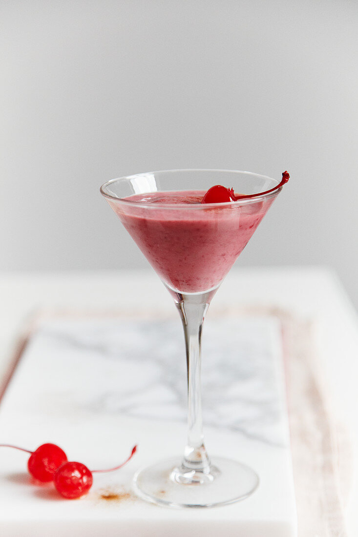 A yoghurt and raspberry drink with liquorice power and cocktail cherries