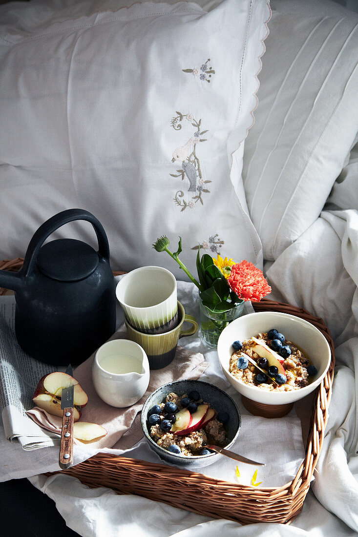 Frühstückstablett mit Müsli, Milch und Tee im Bett
