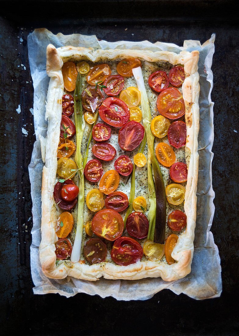 Vegan puff pastry quiche with herb sauce, tomatoes and spring onions
