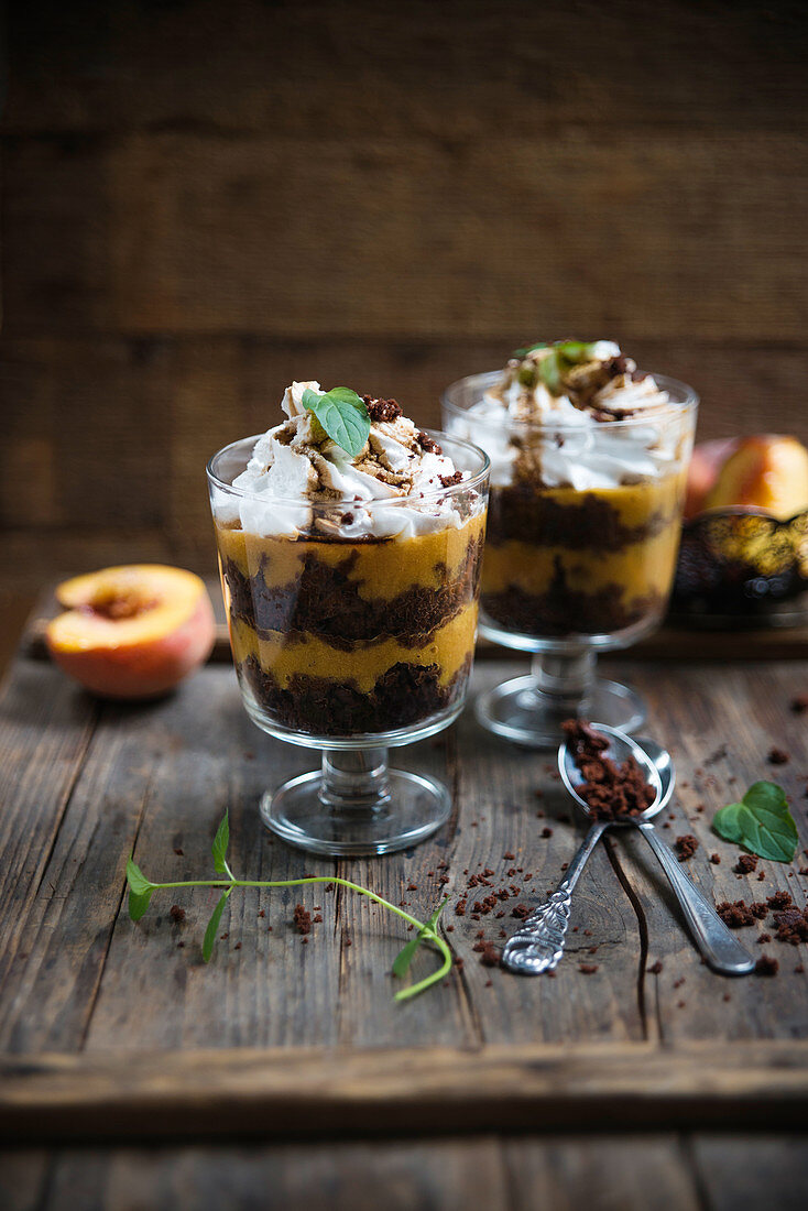 Vegan dessert made from chocolate cake, peach purée, whipped soya cream and coffee syrup in glasses