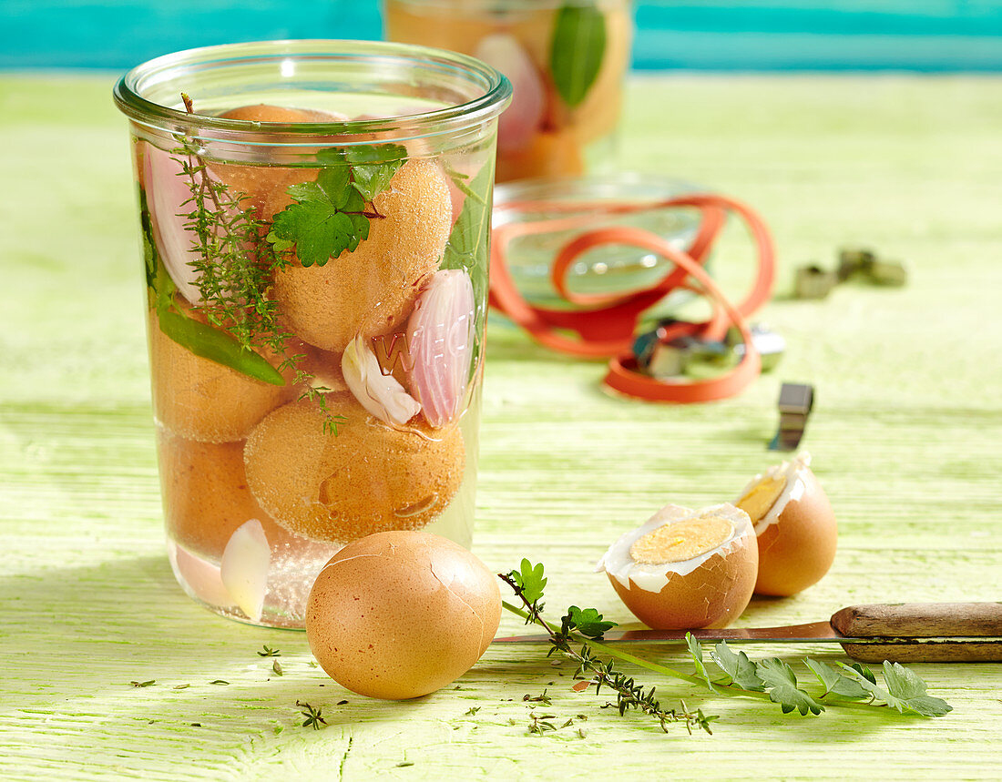 Herb pickled eggs in a jar with bay leaves, onions, garlic, thyme and burnet saxifrage