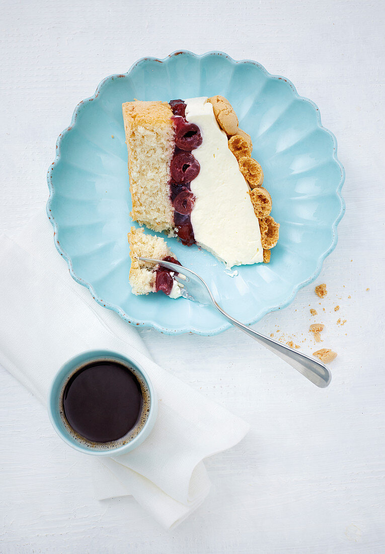 A piece of cherry mascarpone cake served with coffee (top view)