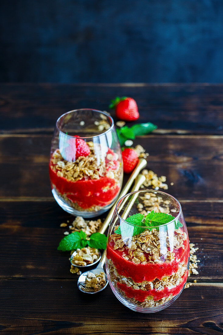 Glasses of granola and strawberries layered parfait with mint for healthy breakfast