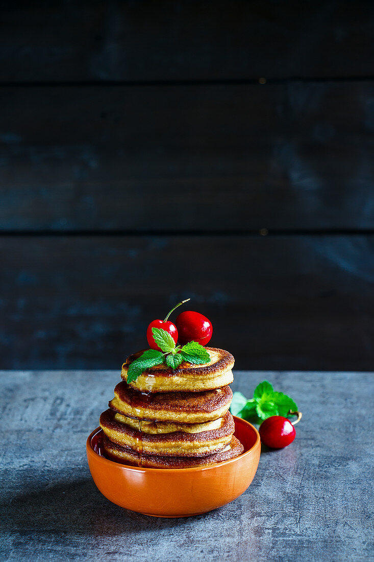 Homemade american pancakes topped with berries, honey and mint leaves
