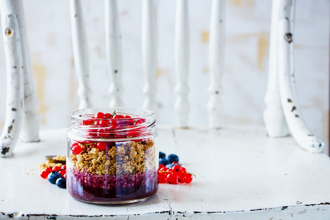 Tasty granola and fresh summer berry layered parfait in jar for breakfast