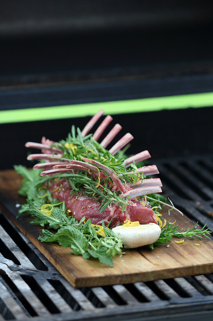 Raw rack of lamb with fresh herbs being prepared for grilling
