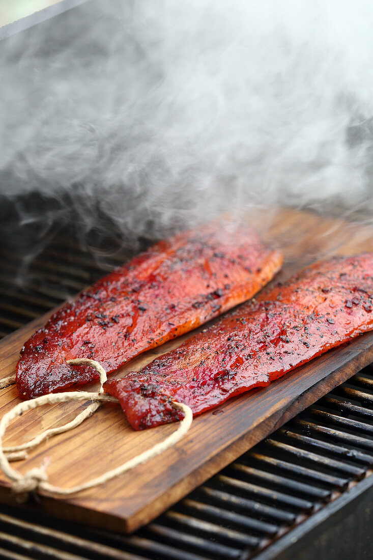 Marinated salmon trout fillers being smoked on a grill