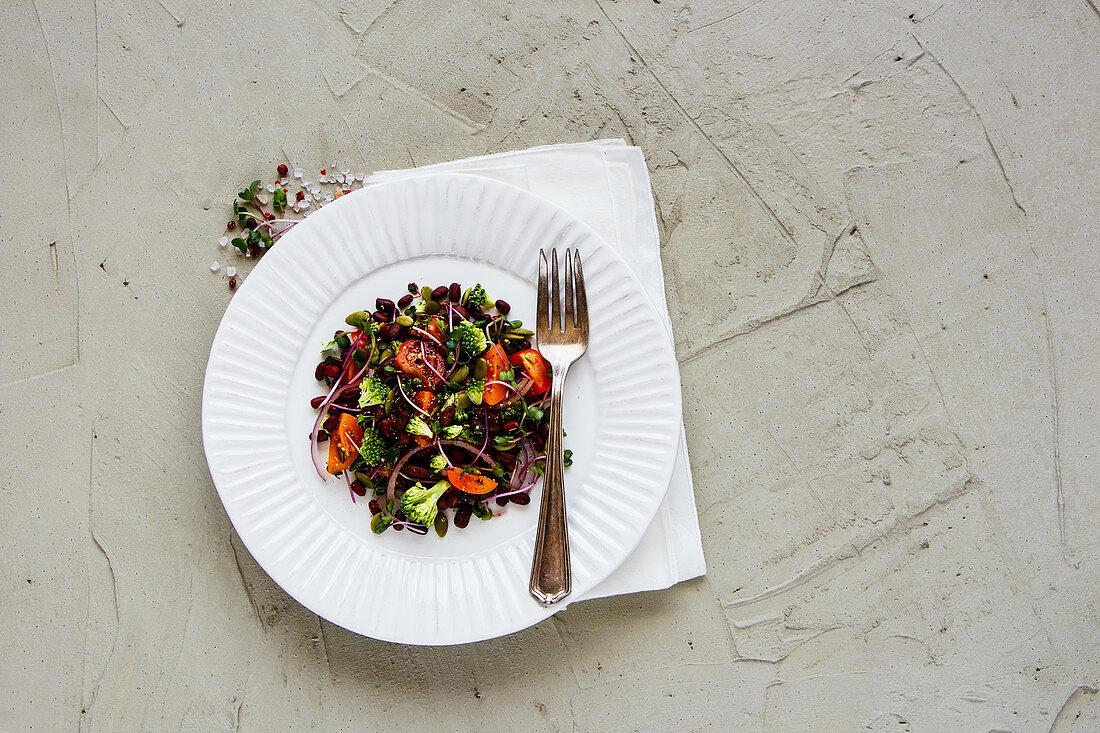 Vegan energy boosting salad with beans, broccoli, tomatoes, red onion, sproots and pumpkin seeds