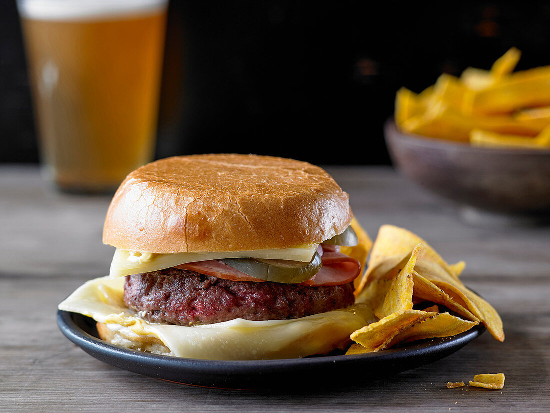 The Bobby Flay Ground Chuck Burger with Ham and Cheese and a side of Banana Chips