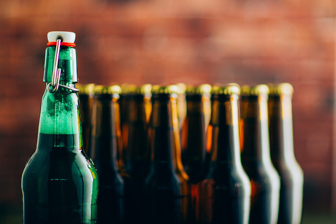 Eine grüne Bierflasche vor vielen braunen Bierflaschen