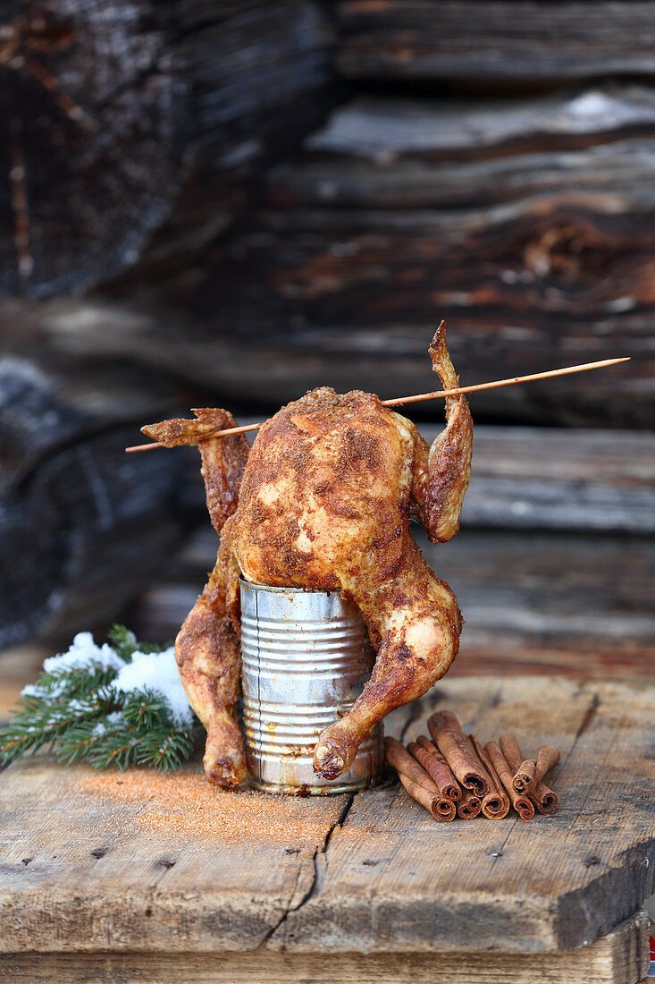 Grilled can chicken on a wooden table outdoors