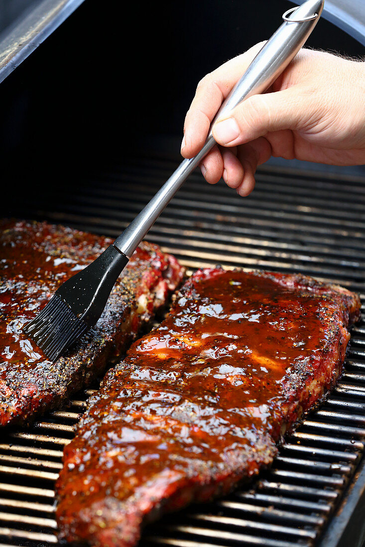 Beef Briskets auf dem Grill mit BBQ-Sauce einpinseln