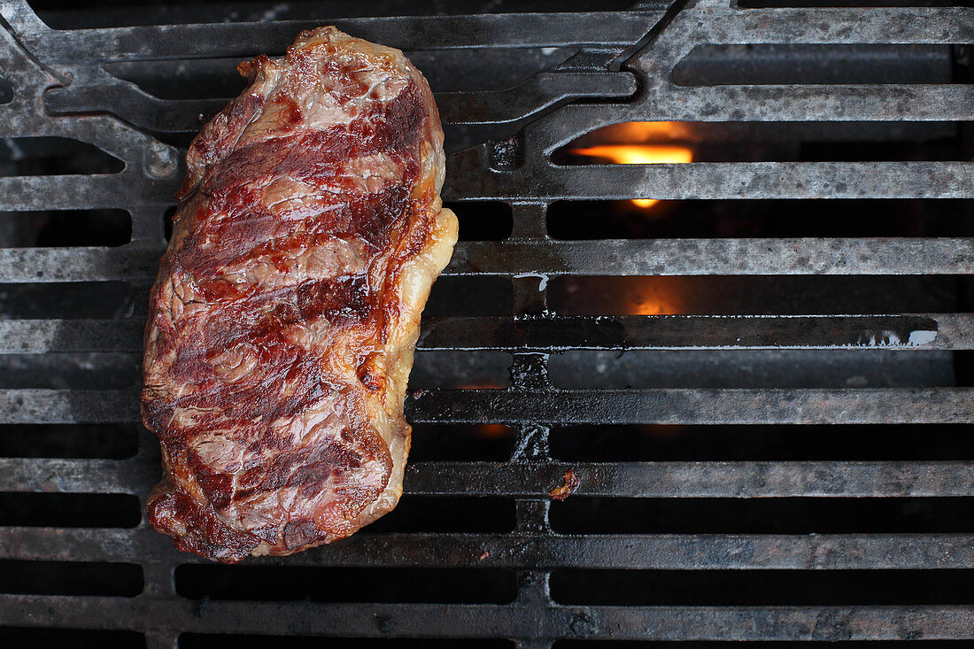 Grilled beef steak on a barbecue (seen from above)