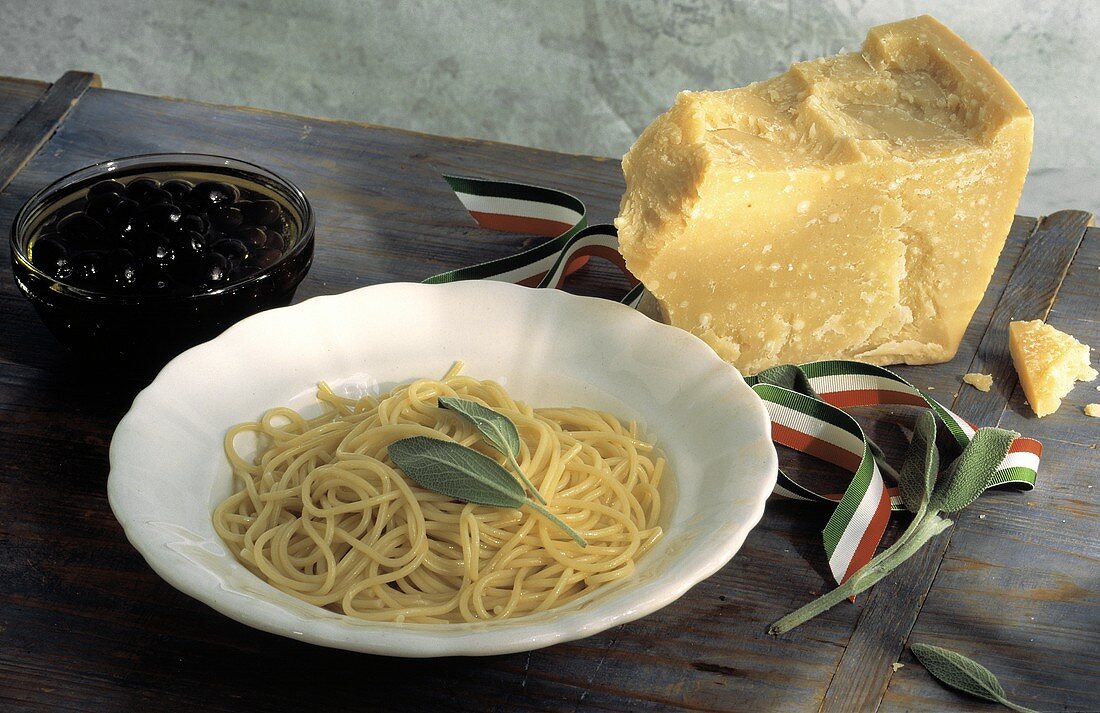 Butterspaghetti mit Salbei auf Teller neben Parmesan & Oliven
