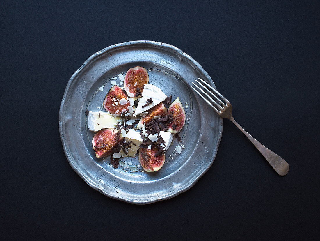 Dessert consisting of fresh figs and brie cheese with honey, almond petals and chocolate chips