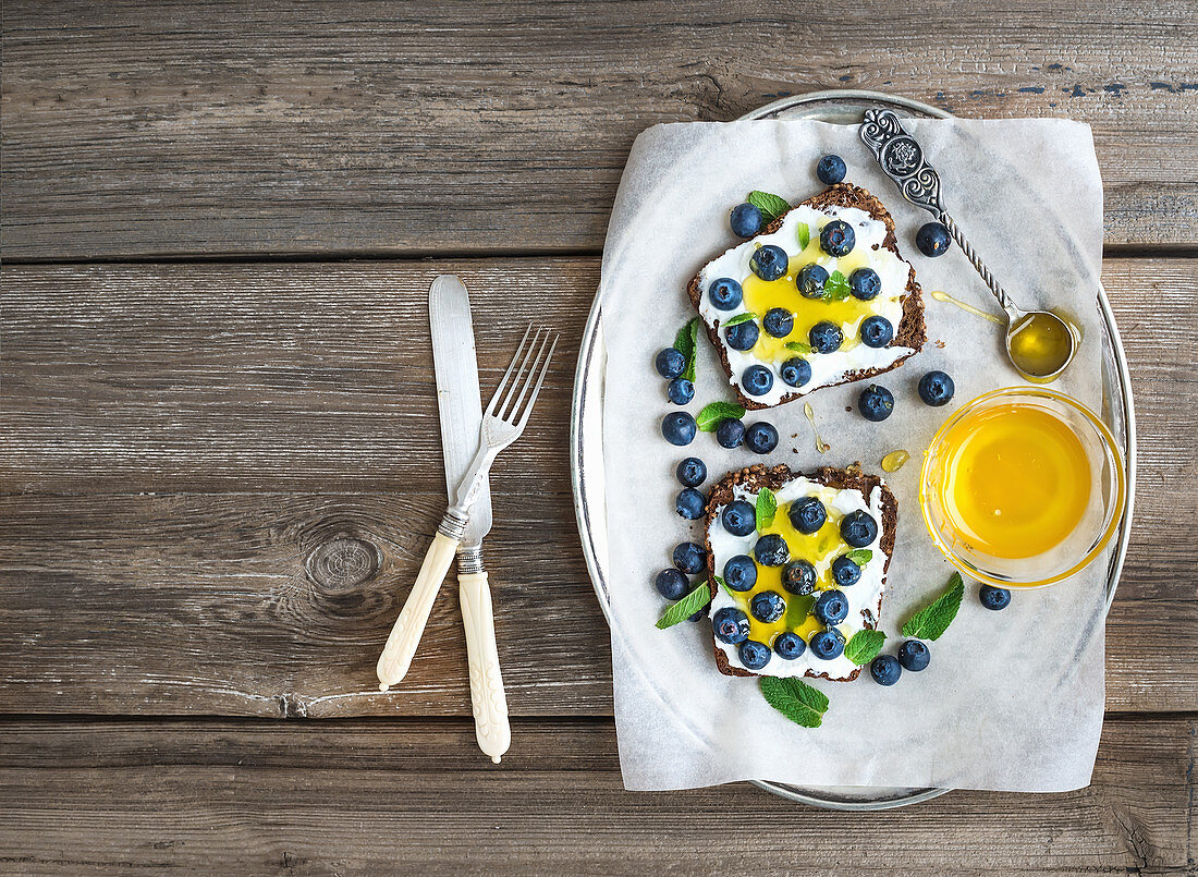 Healthy breakfast set with ricotta, fresh blueberries and honey sandwiches on whole grain bread