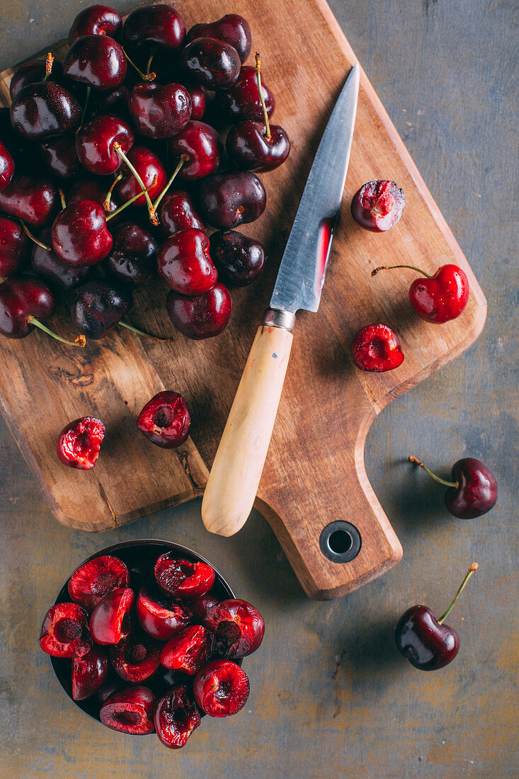 Frische Kirschen auf Holzschneidebrett mit Messer entsteinen